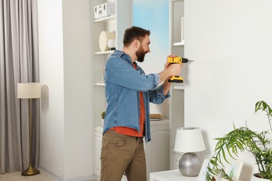 Photo of Man working with drill and wall at home