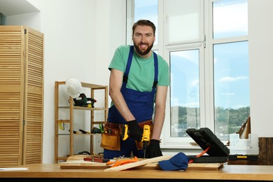 Photo of Portrait of smiling craftsman with drill at table in workshop