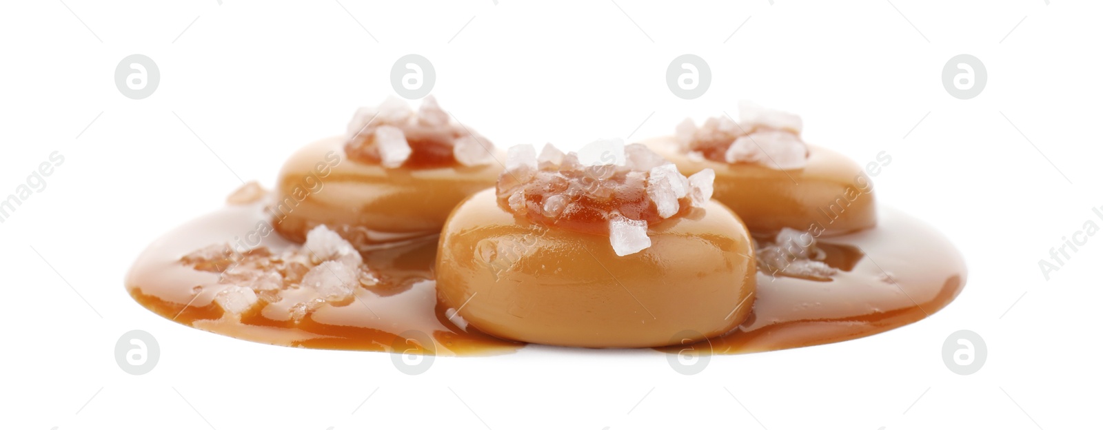 Photo of Yummy candies with caramel sauce and sea salt isolated on white