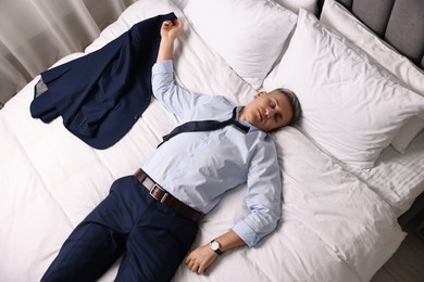 Photo of Businessman in office clothes sleeping on bed indoors, top view