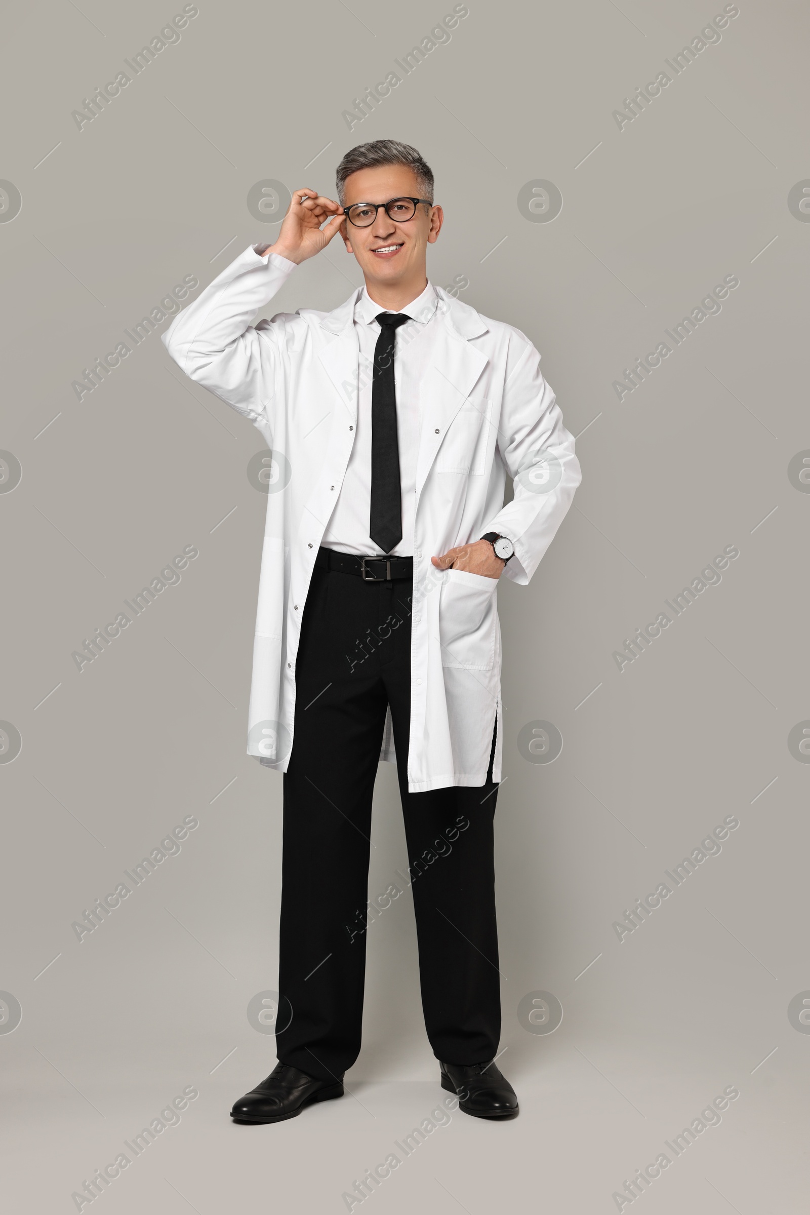 Photo of Happy doctor in glasses on grey background