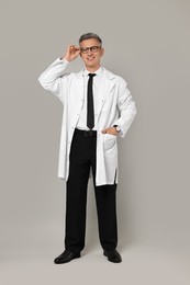 Photo of Happy doctor in glasses on grey background