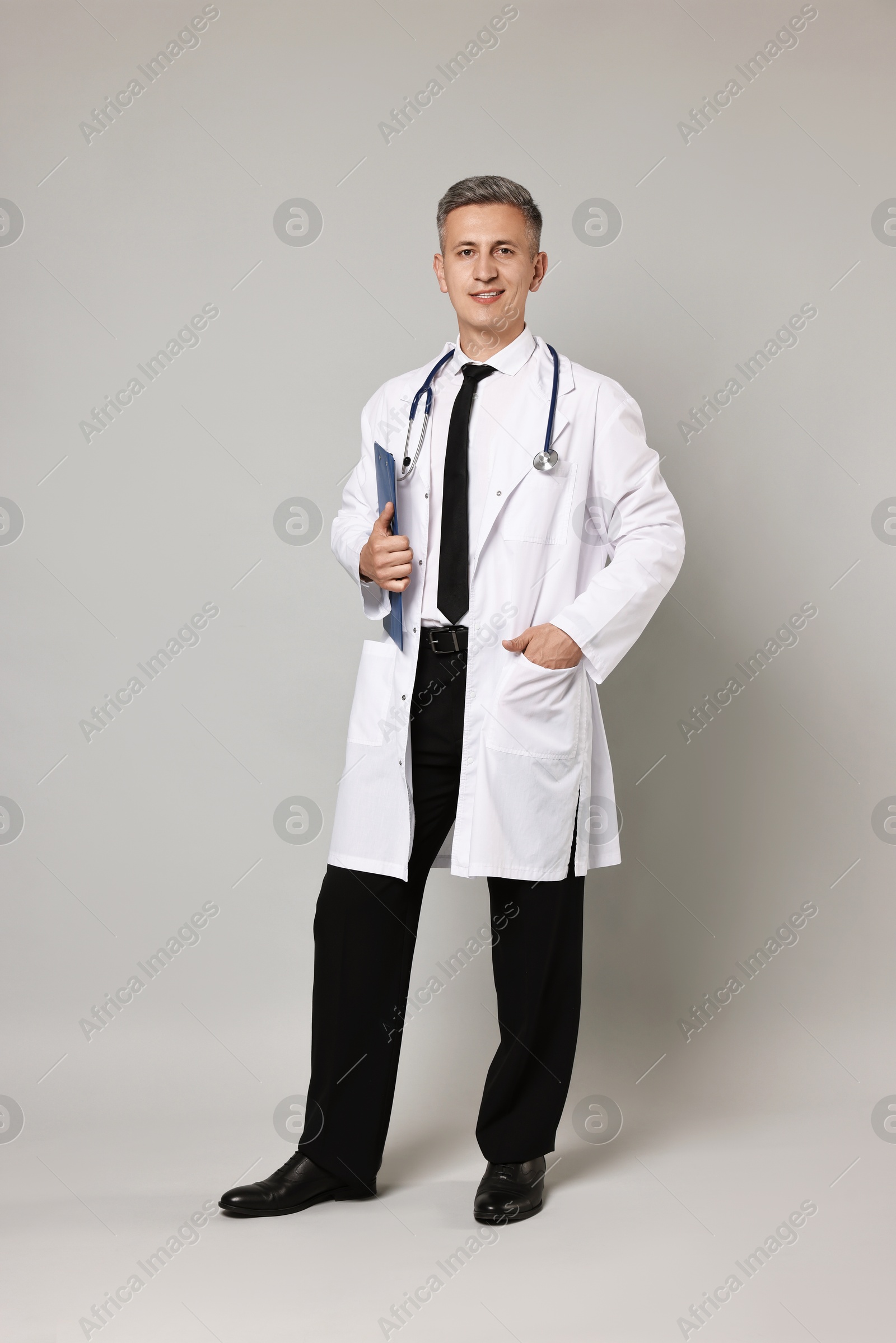 Photo of Doctor with stethoscope and clipboard on grey background