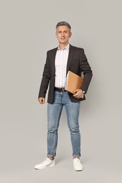 Happy teacher with notebooks on grey background