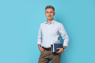 Teacher with books on light blue background