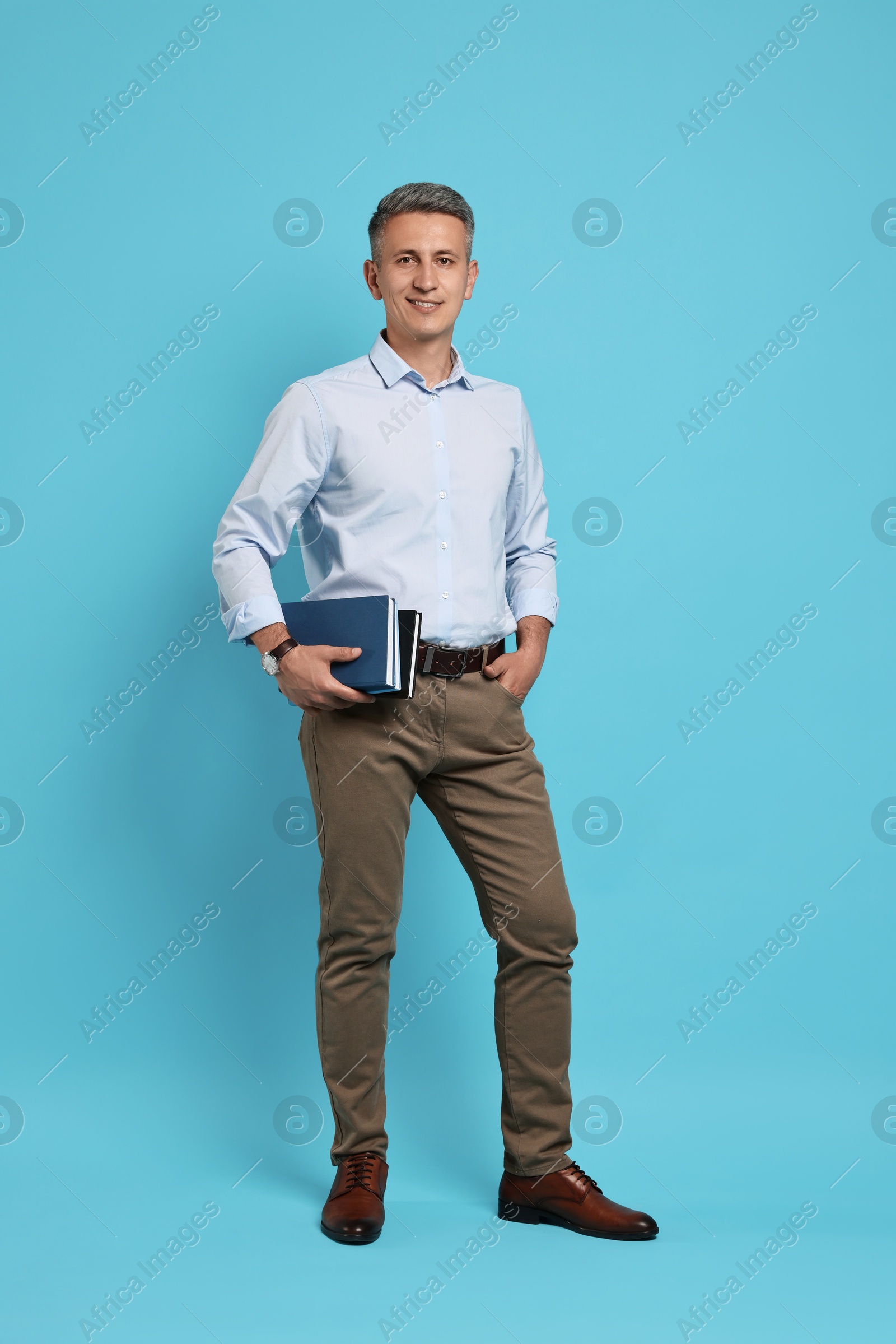 Photo of Teacher with books on light blue background