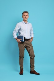 Teacher with books on light blue background