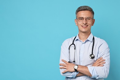 Doctor with stethoscope on light blue background, space for text