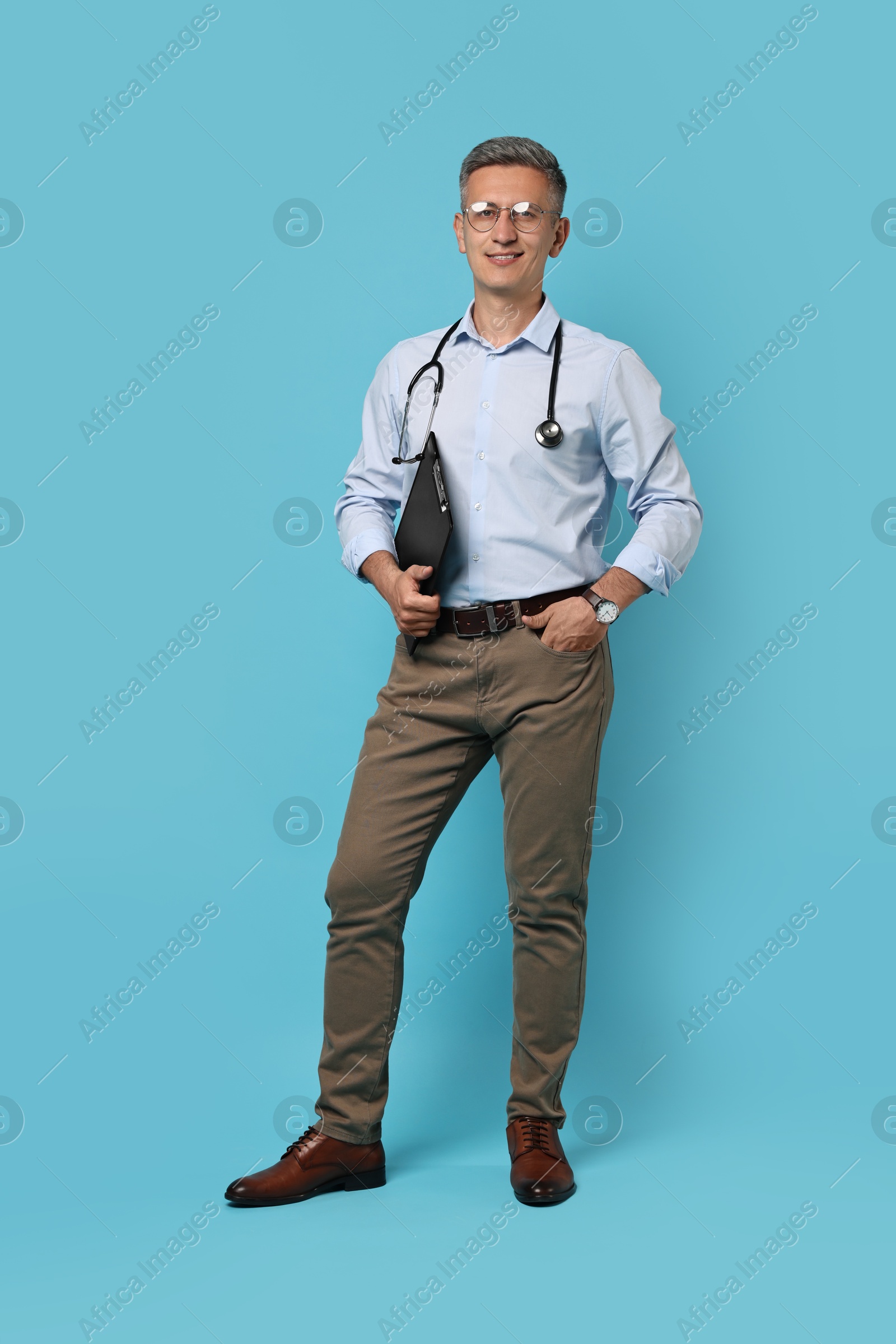 Photo of Doctor with stethoscope and clipboard on light blue background