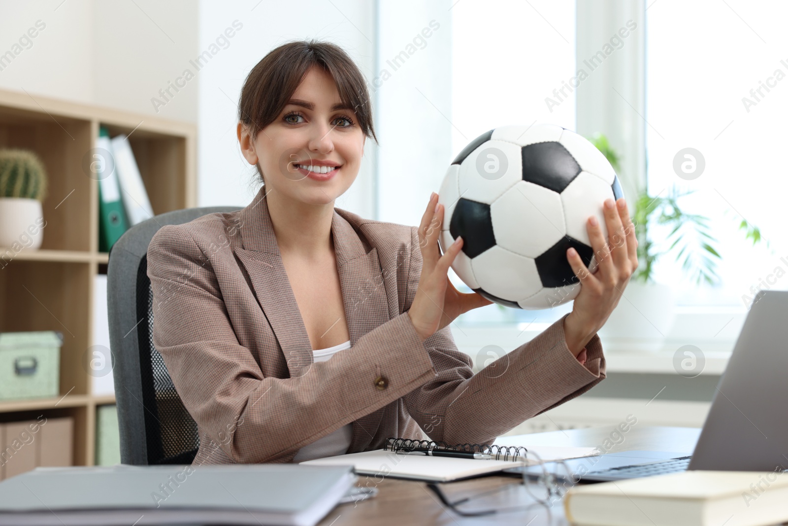 Photo of Smiling employee with soccer ball at table in office