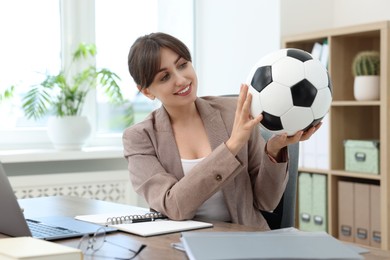 Photo of Smiling employee with soccer ball at table in office