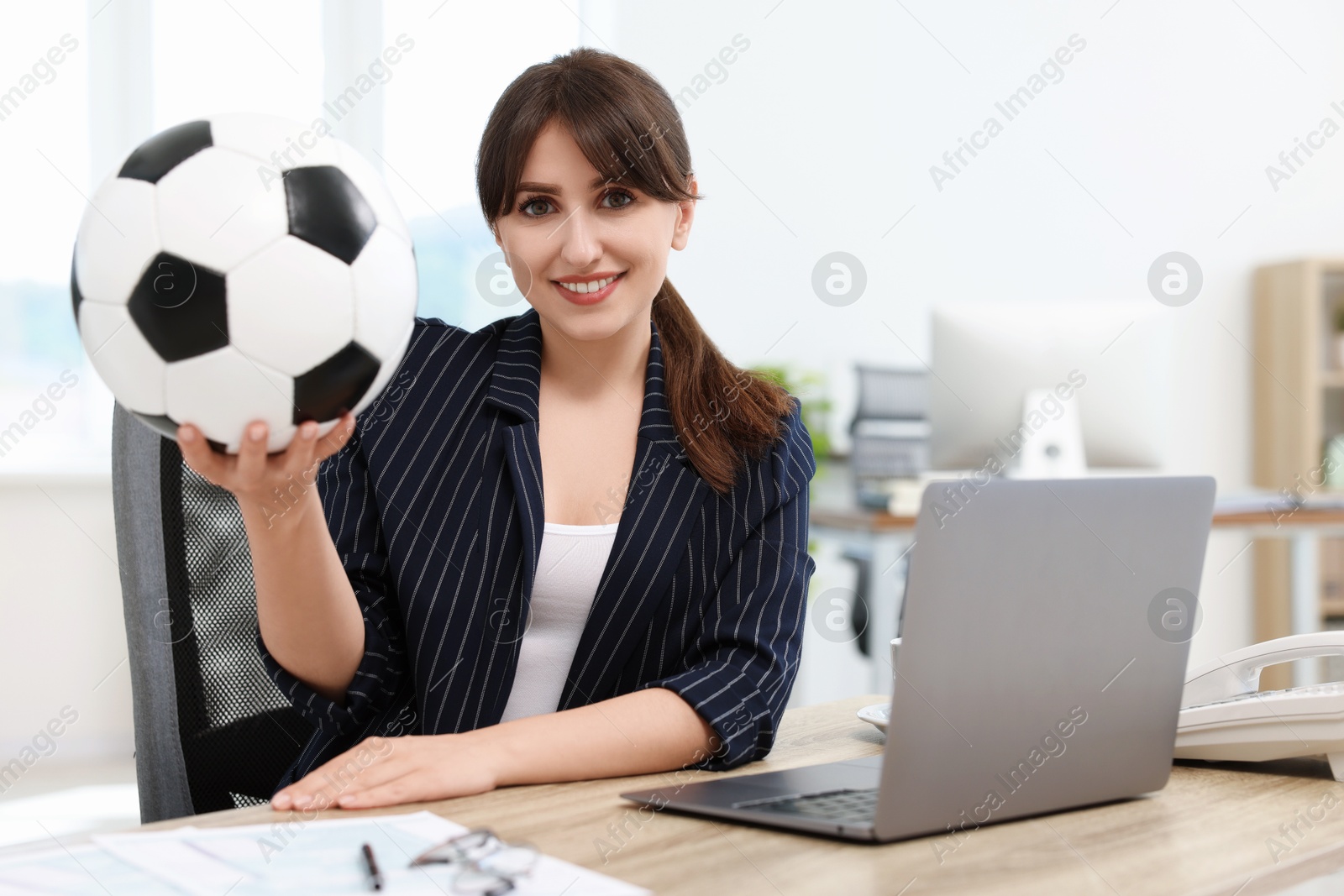 Photo of Smiling employee with soccer ball at table in office