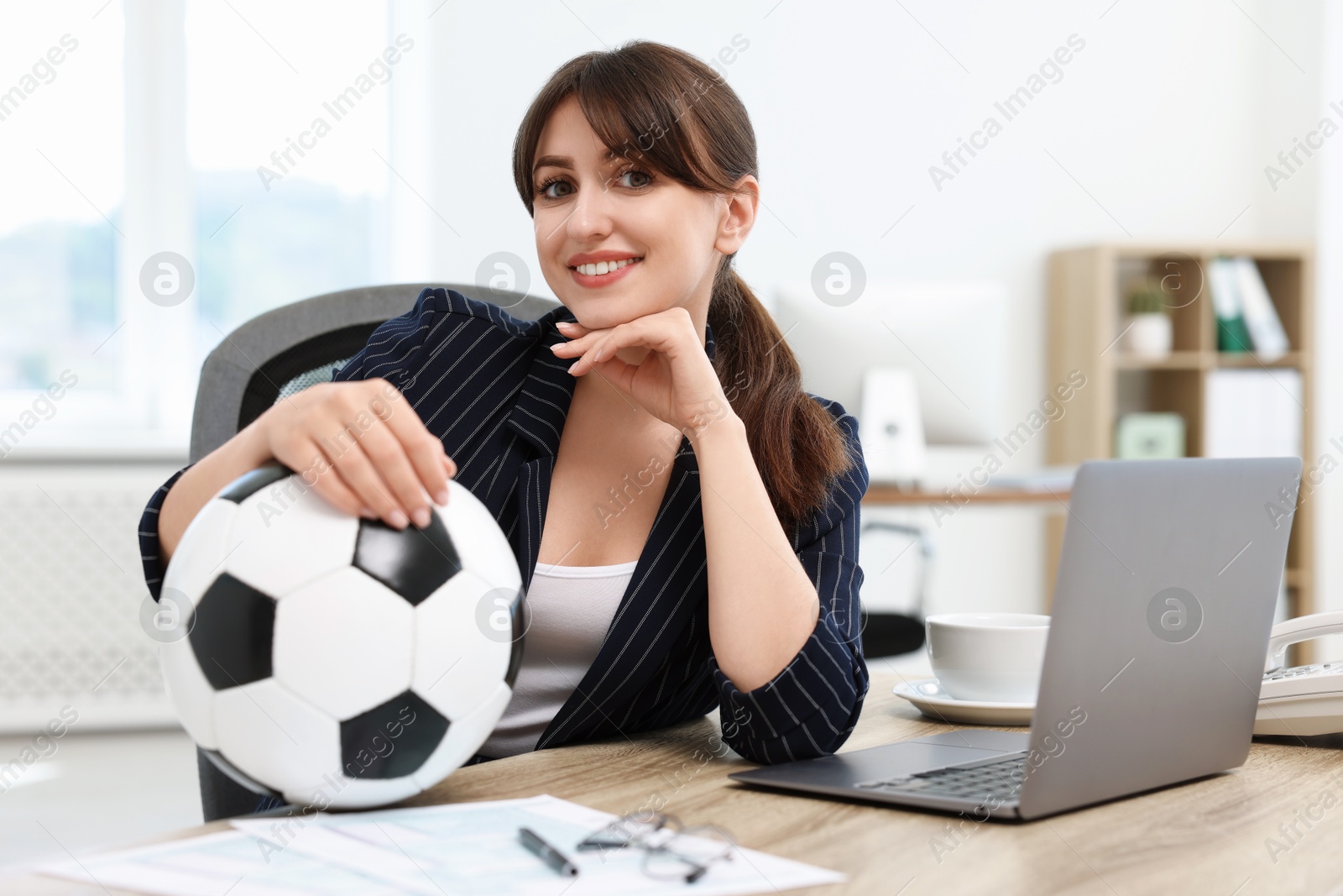 Photo of Smiling employee with soccer ball at table in office