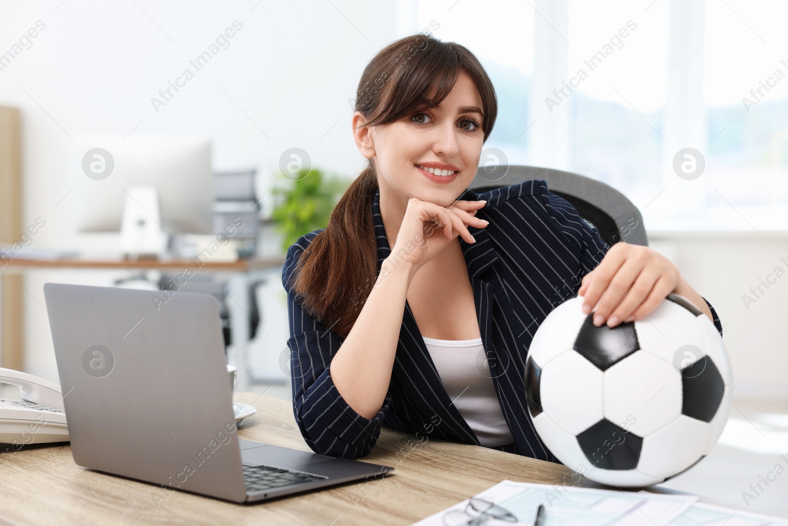 Photo of Smiling employee with soccer ball at table in office