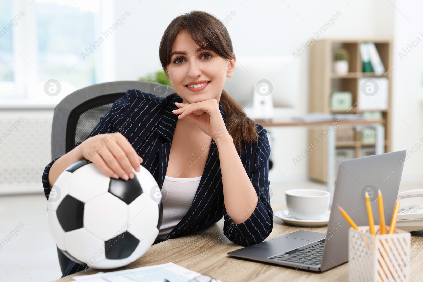 Photo of Smiling employee with soccer ball at table in office