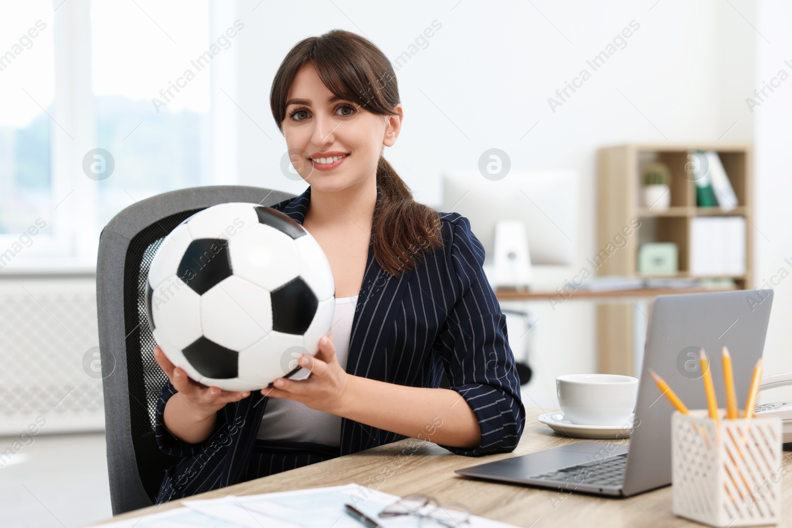 Photo of Smiling employee with soccer ball at table in office