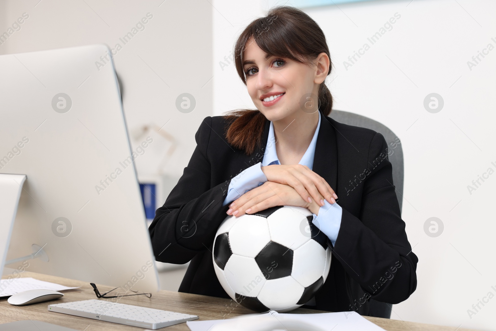 Photo of Smiling employee with soccer ball at table in office