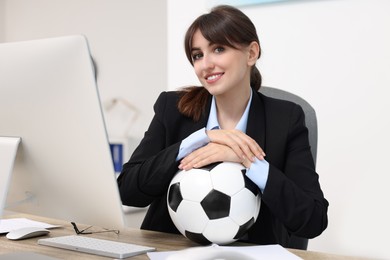 Smiling employee with soccer ball at table in office