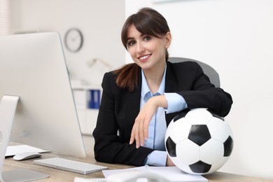 Smiling employee with soccer ball at table in office