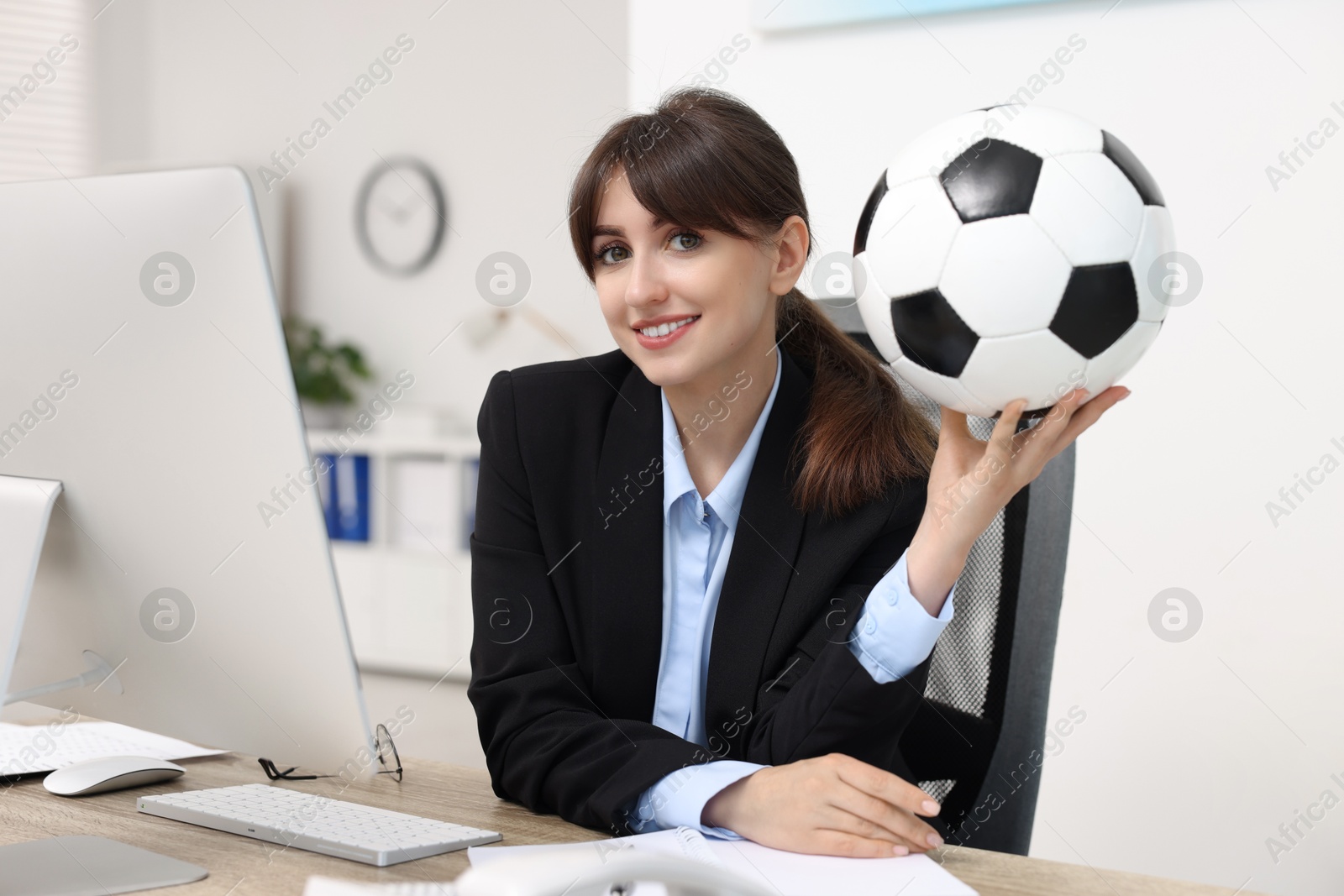 Photo of Smiling employee with soccer ball at table in office