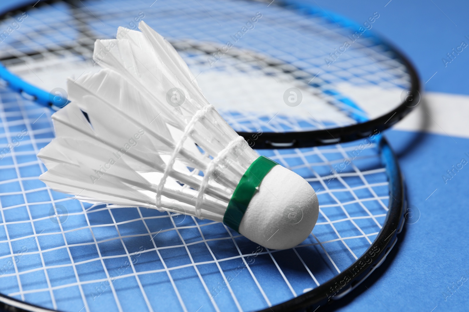 Photo of Feather badminton shuttlecock and rackets on court, closeup