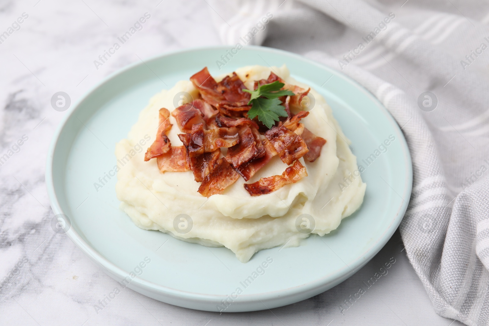 Photo of Fried bacon, mashed potato and parsley on white marble table