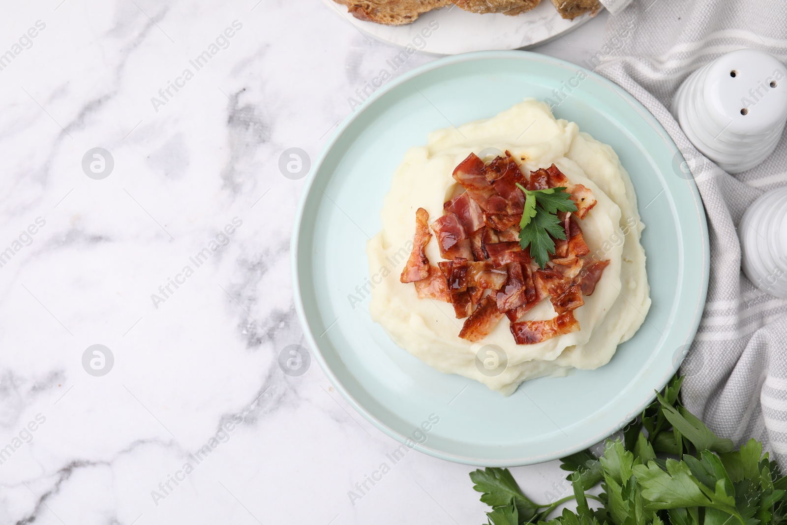 Photo of Fried bacon, mashed potato and parsley on white marble table, top view. Space for text