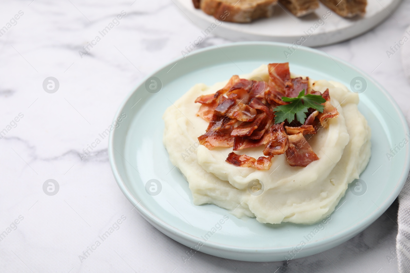 Photo of Fried bacon, mashed potato and parsley on white marble table. Space for text