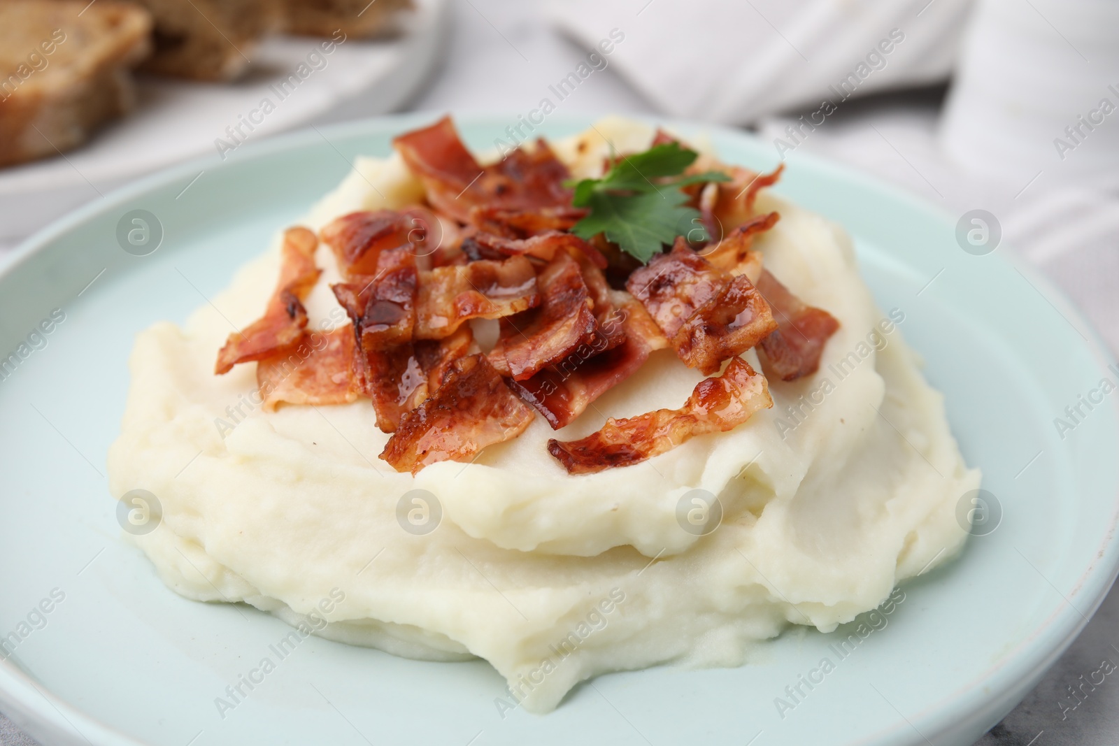 Photo of Fried bacon, mashed potato and parsley on table, closeup