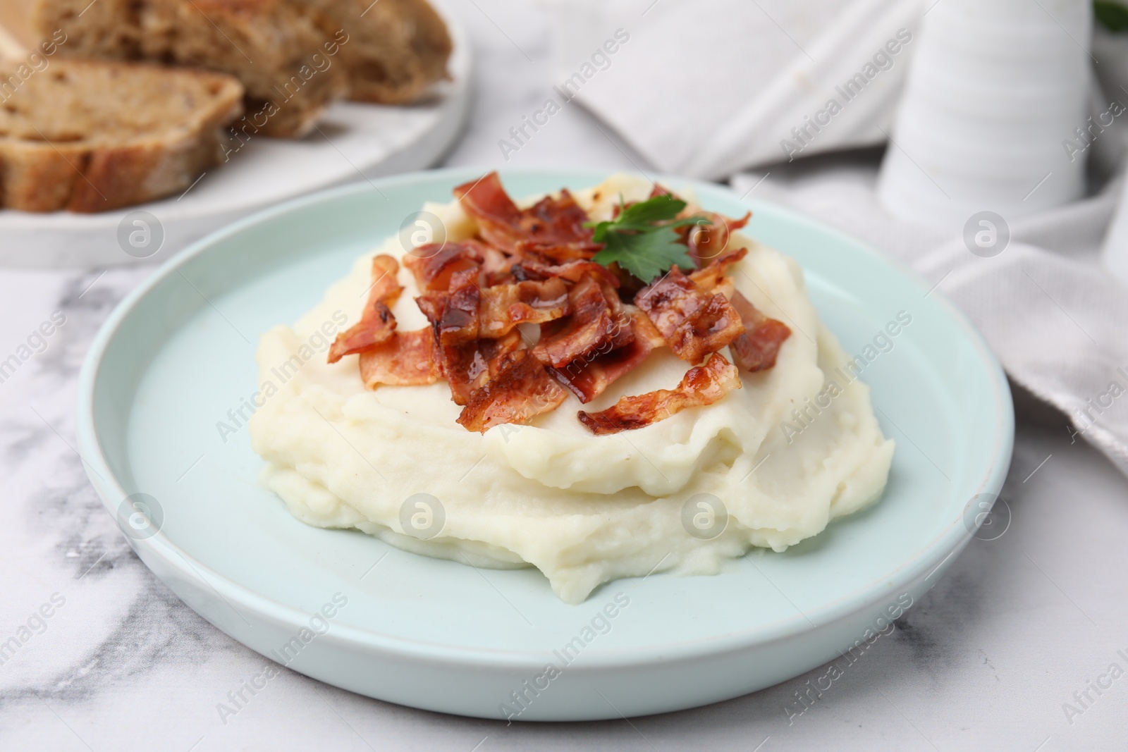 Photo of Fried bacon, mashed potato and parsley on white marble table