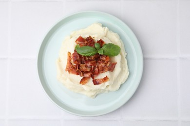 Photo of Fried bacon, mashed potato and basil on white tiled table, top view