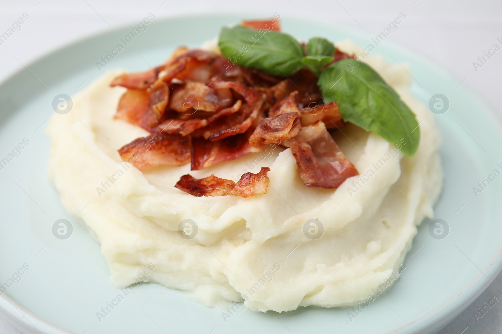 Photo of Fried bacon, mashed potato and basil on table, closeup