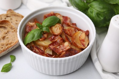 Delicious baked potatoes, bacon, basil and bread on white table