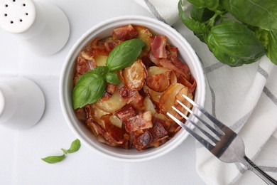 Delicious baked potatoes, bacon, basil and fork on white table, top view