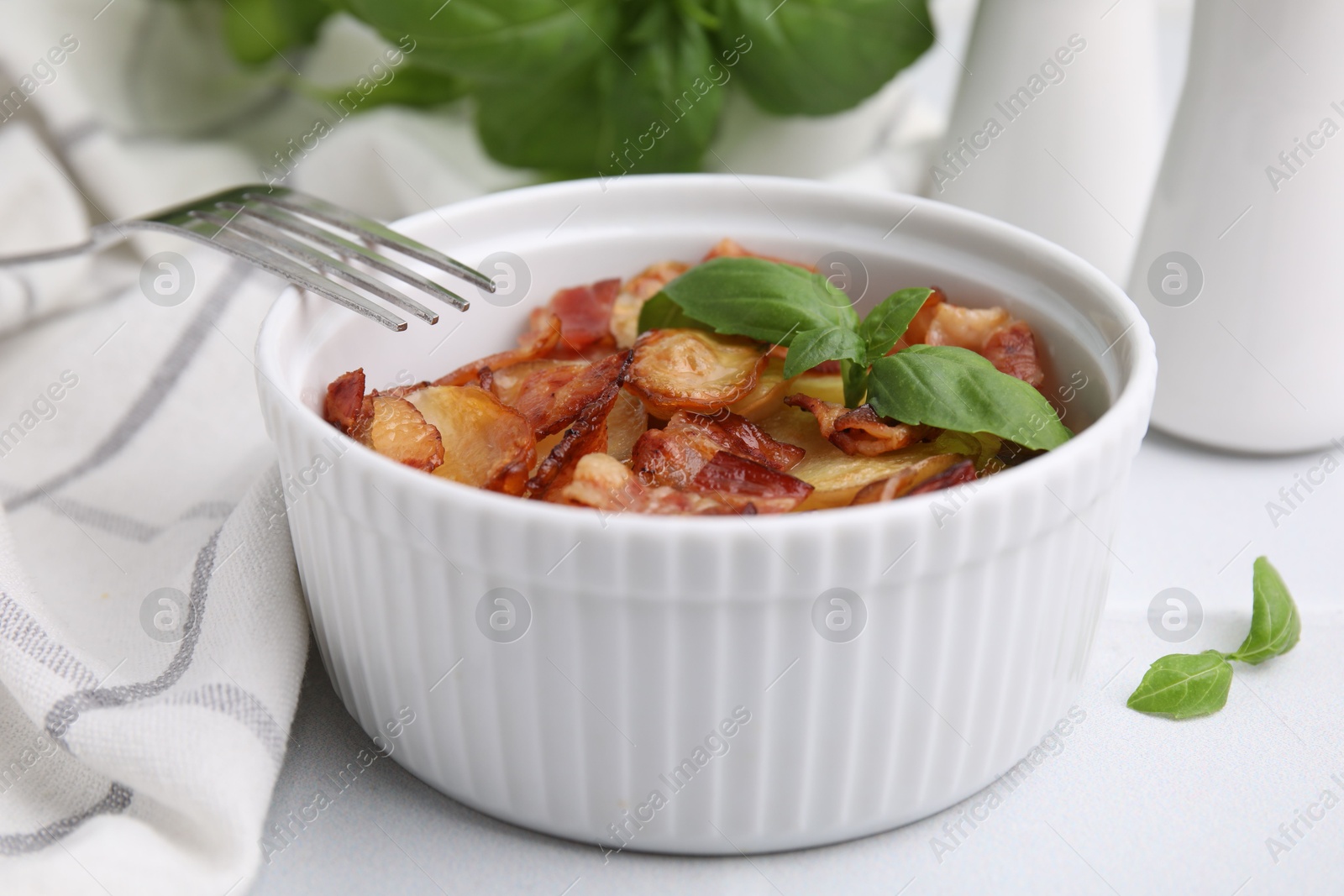 Photo of Delicious baked potatoes, bacon, basil and fork on white table