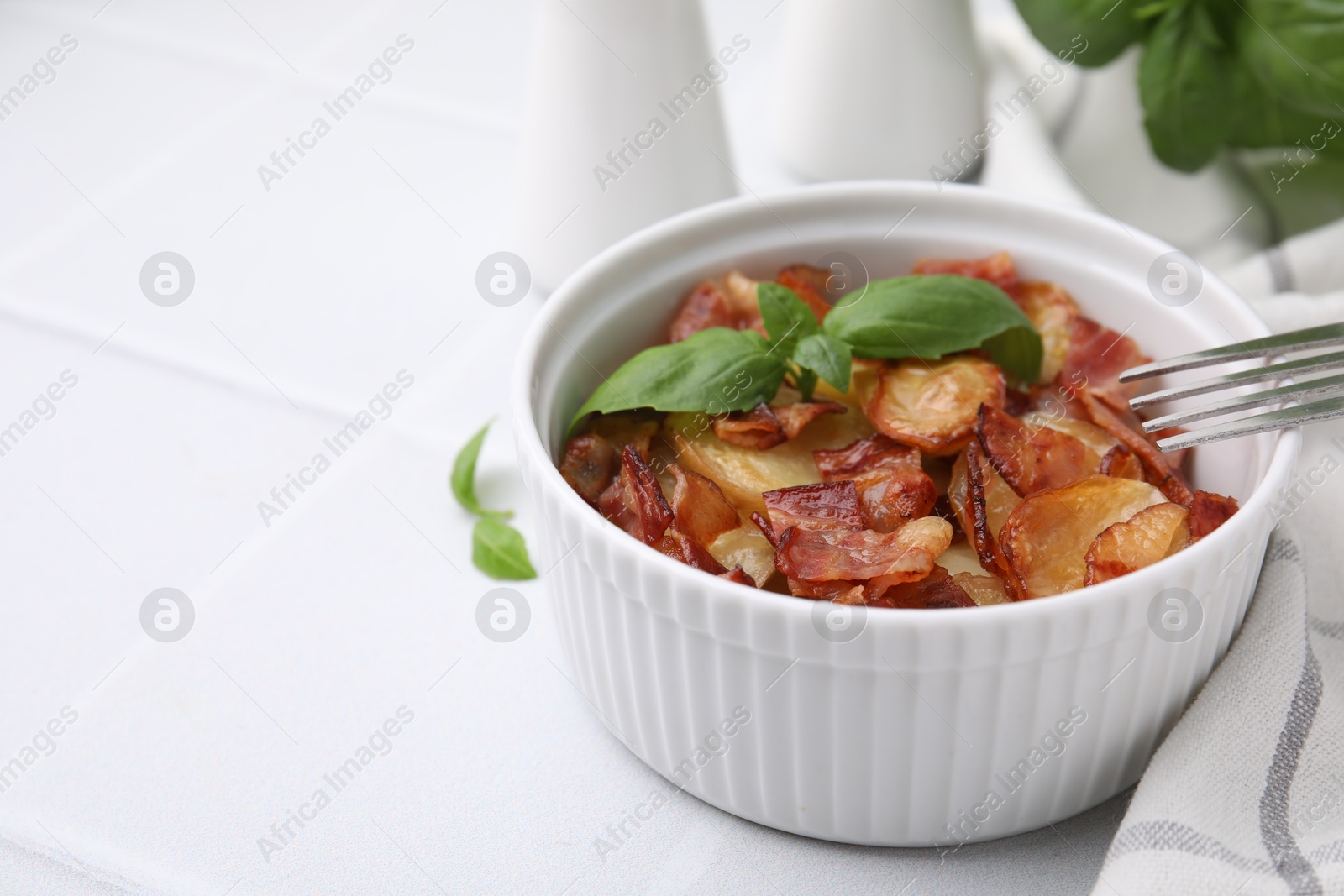 Photo of Delicious baked potatoes, bacon, basil and fork on white table, space for text