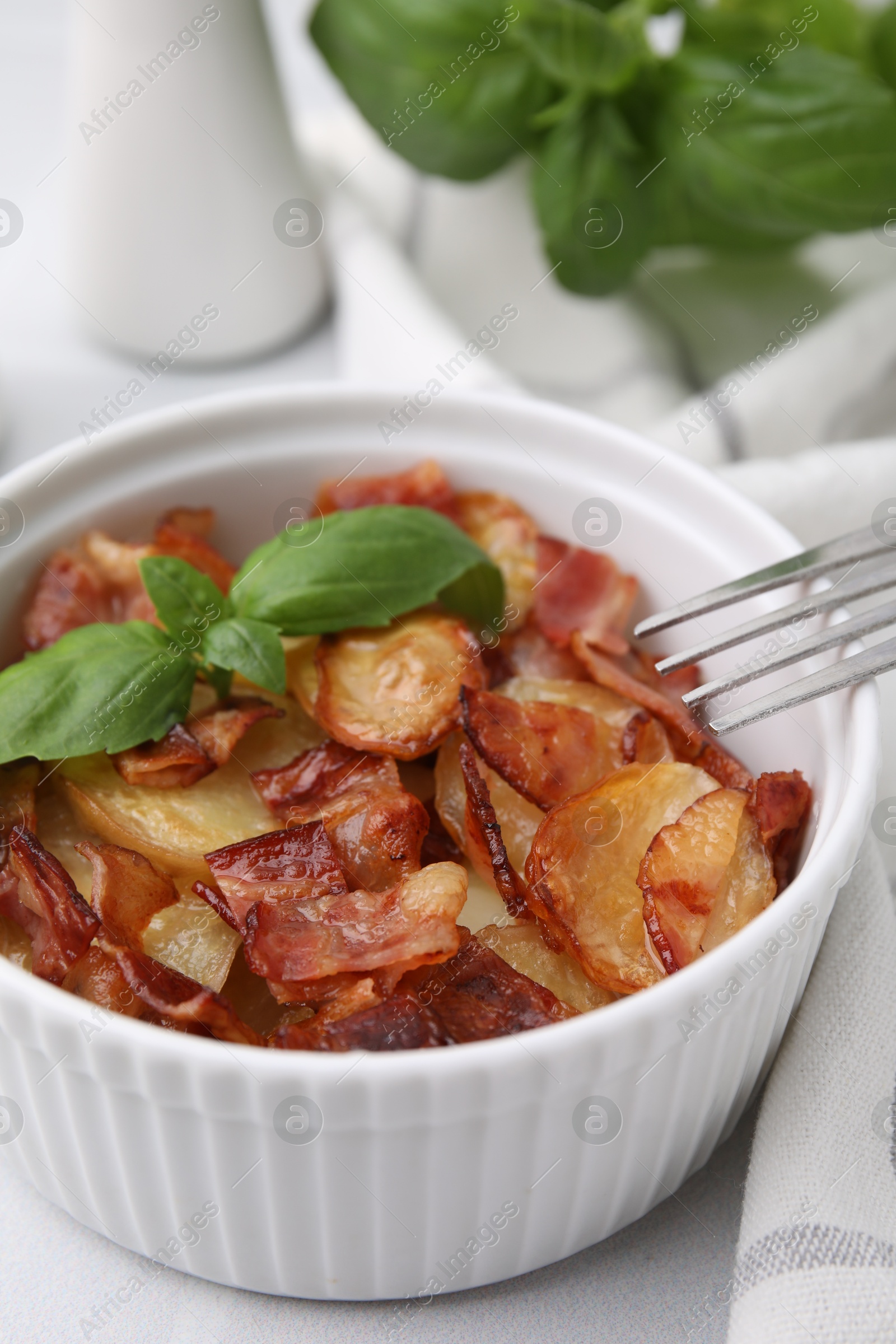 Photo of Delicious baked potatoes, bacon, basil and fork on white table, closeup