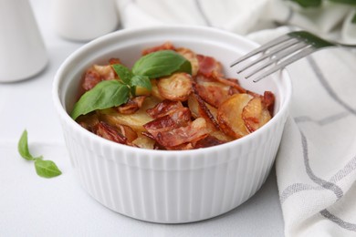 Delicious baked potatoes, bacon, basil and fork on white table