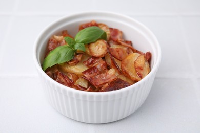 Photo of Delicious baked potatoes, bacon and basil in bowl on white table