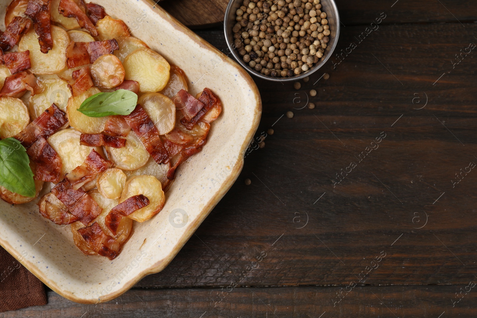 Photo of Delicious baked potatoes, bacon, basil and peppercorns on wooden table, top view. Space for text