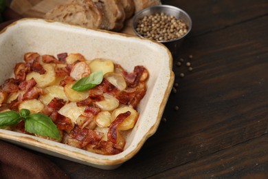 Photo of Delicious baked potatoes, bacon, basil, peppercorns and bread on wooden table, space for text