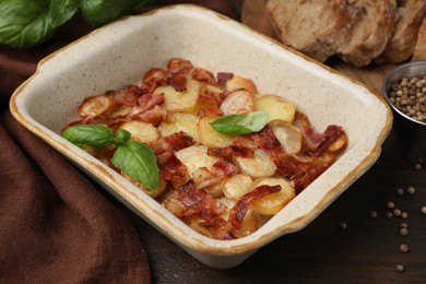 Delicious baked potatoes, bacon, basil, peppercorns and bread on wooden table