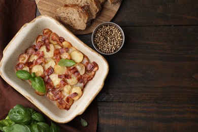 Photo of Delicious baked potatoes, bacon, basil, peppercorns and bread on wooden table, top view. Space for text