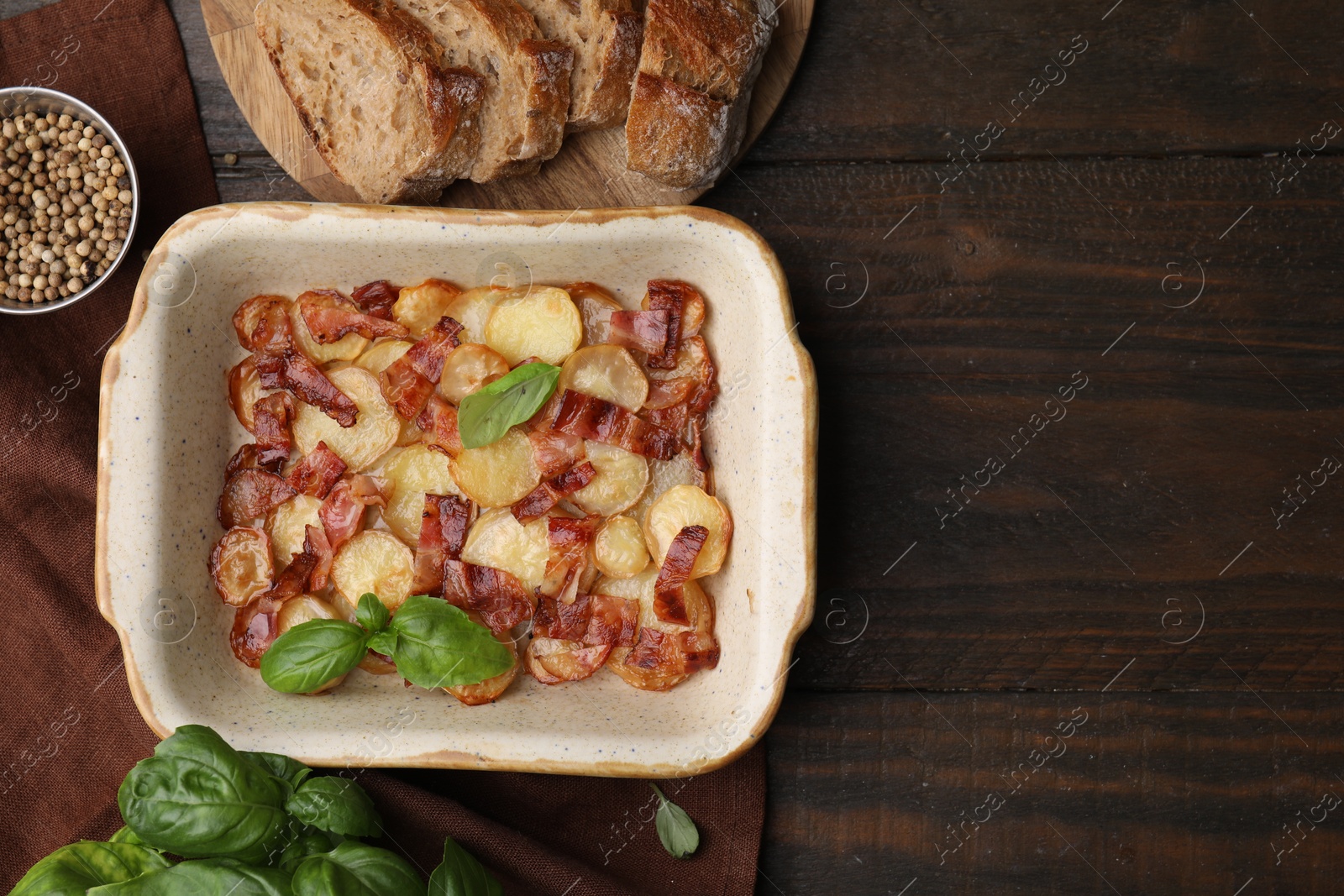 Photo of Delicious baked potatoes, bacon, basil, peppercorns and bread on wooden table, top view. Space for text