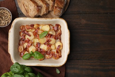 Delicious baked potatoes, bacon, basil, peppercorns and bread on wooden table, top view. Space for text