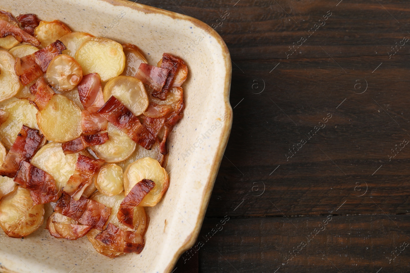 Photo of Delicious baked potatoes and bacon in baking dish on wooden table, top view. Space for text