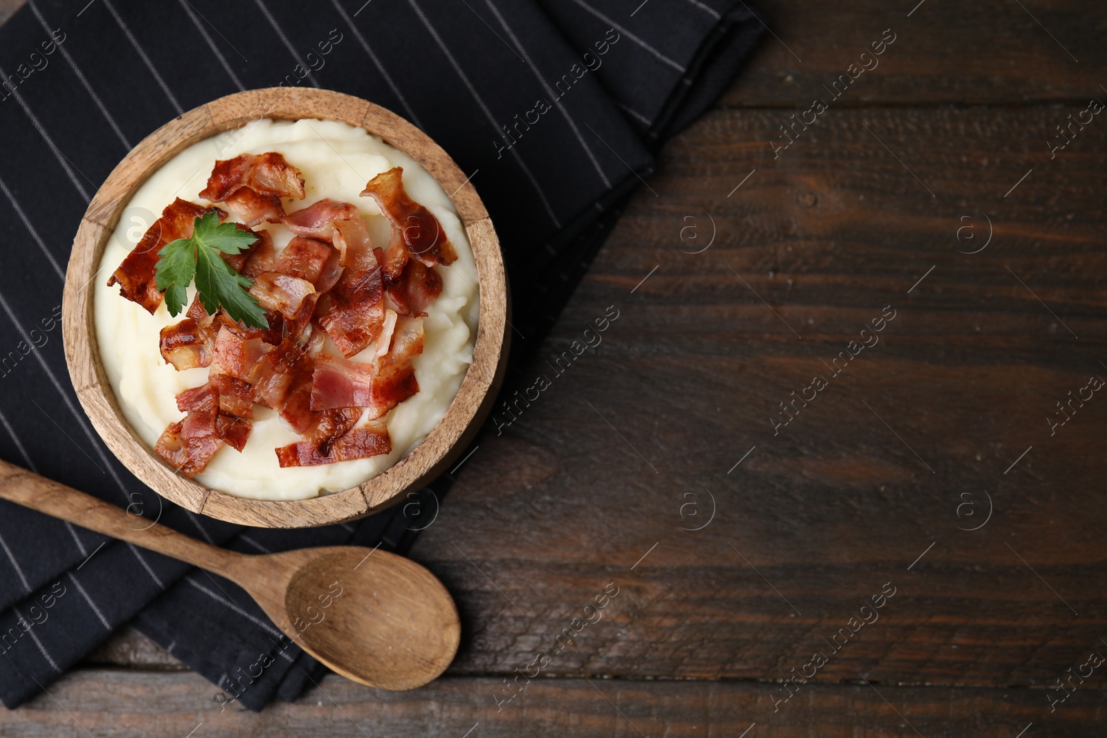 Photo of Fried bacon, mashed potato and spoon on wooden table, top view. Space for text