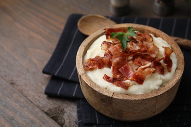 Fried bacon, mashed potato and parsley in bowl on wooden table. Space for text