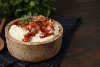 Photo of Fried bacon, mashed potato and parsley in bowl on wooden table. Space for text