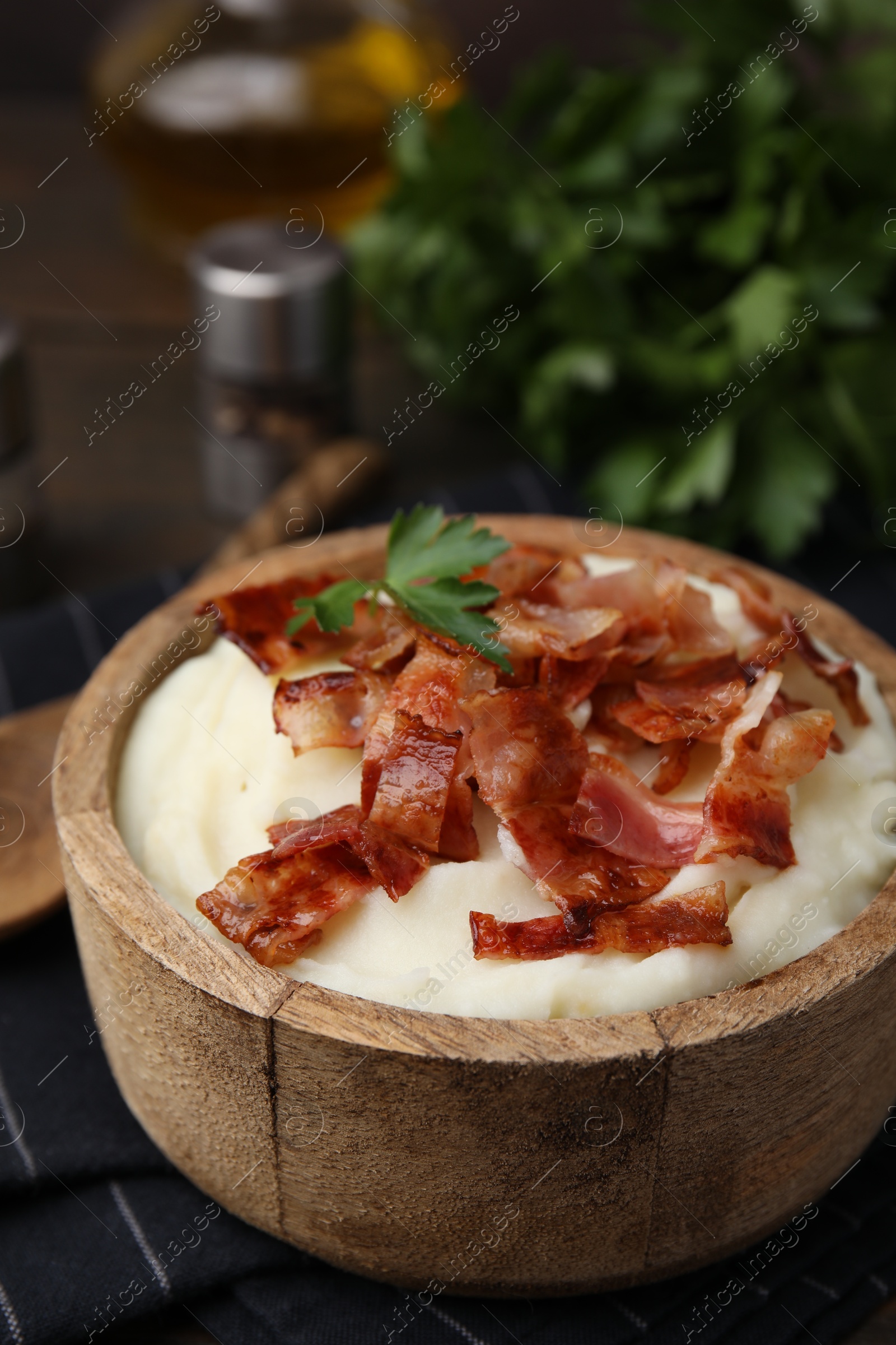 Photo of Fried bacon, mashed potato and parsley in bowl on table